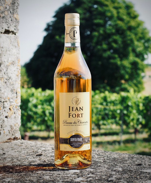 Bouteilles de Pineau des Charentes blanc et rosé du producteur Jean Fort, avec des verres de dégustation.